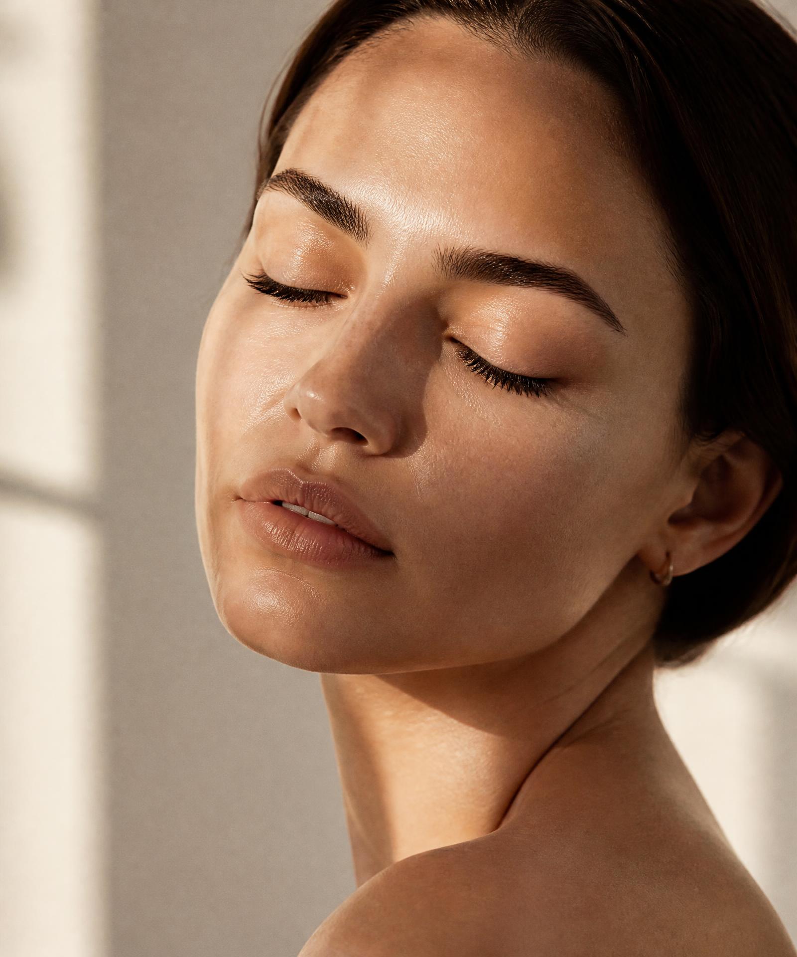 Editorial beauty portrait of a woman with luminous skin and softly groomed brows at Maison Aesthetics Calgary